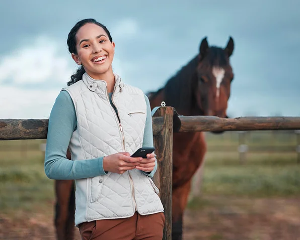 propriétaire de cheval utilisant une application mobile près de son cheval dans l'écurie